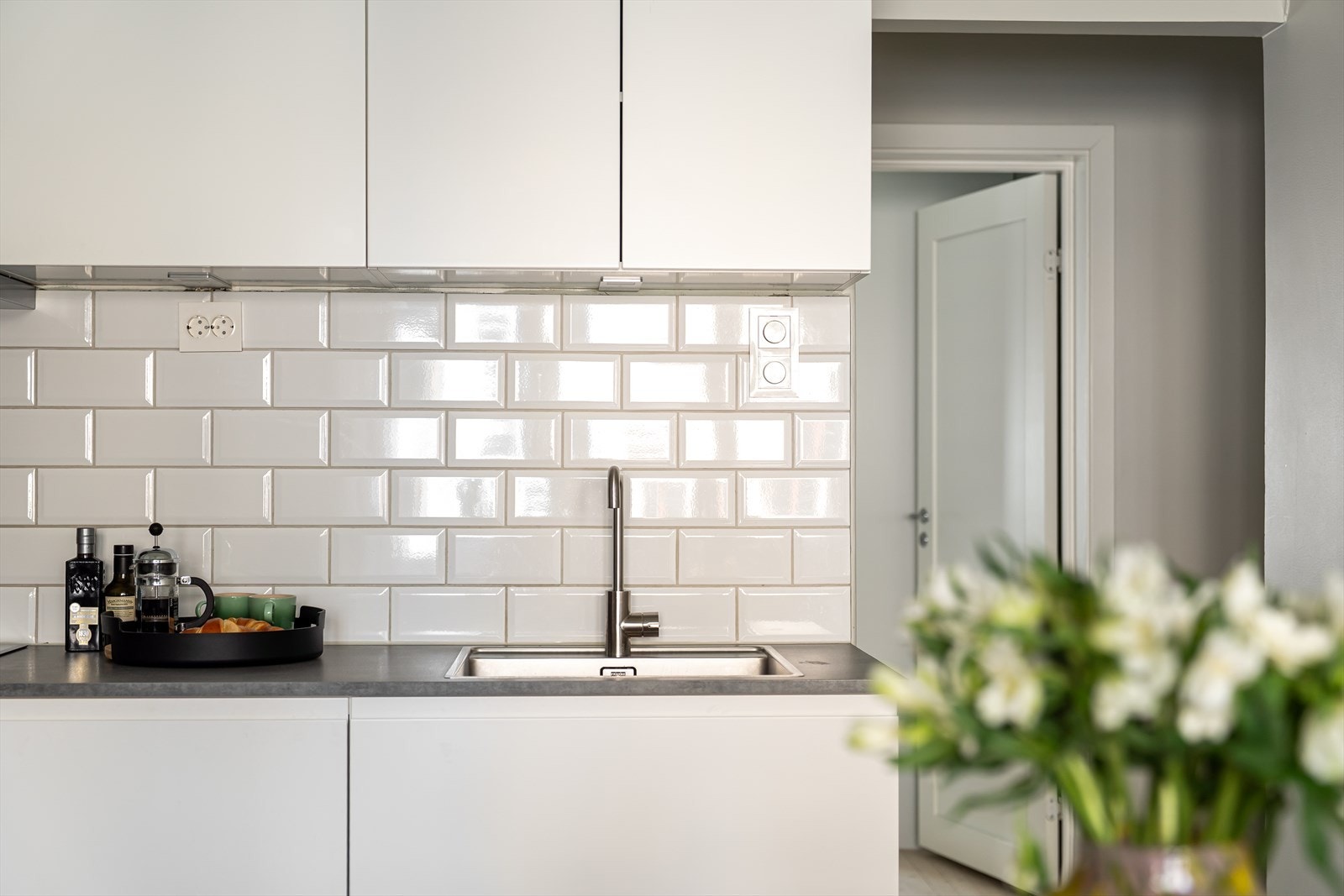 Kjøkkenet ble flyttet og fornyet i 2023 og er innredet med stilren Kvik-innredning og nøytrale hvite fliser over kjøkkenbenk. Galleribilde