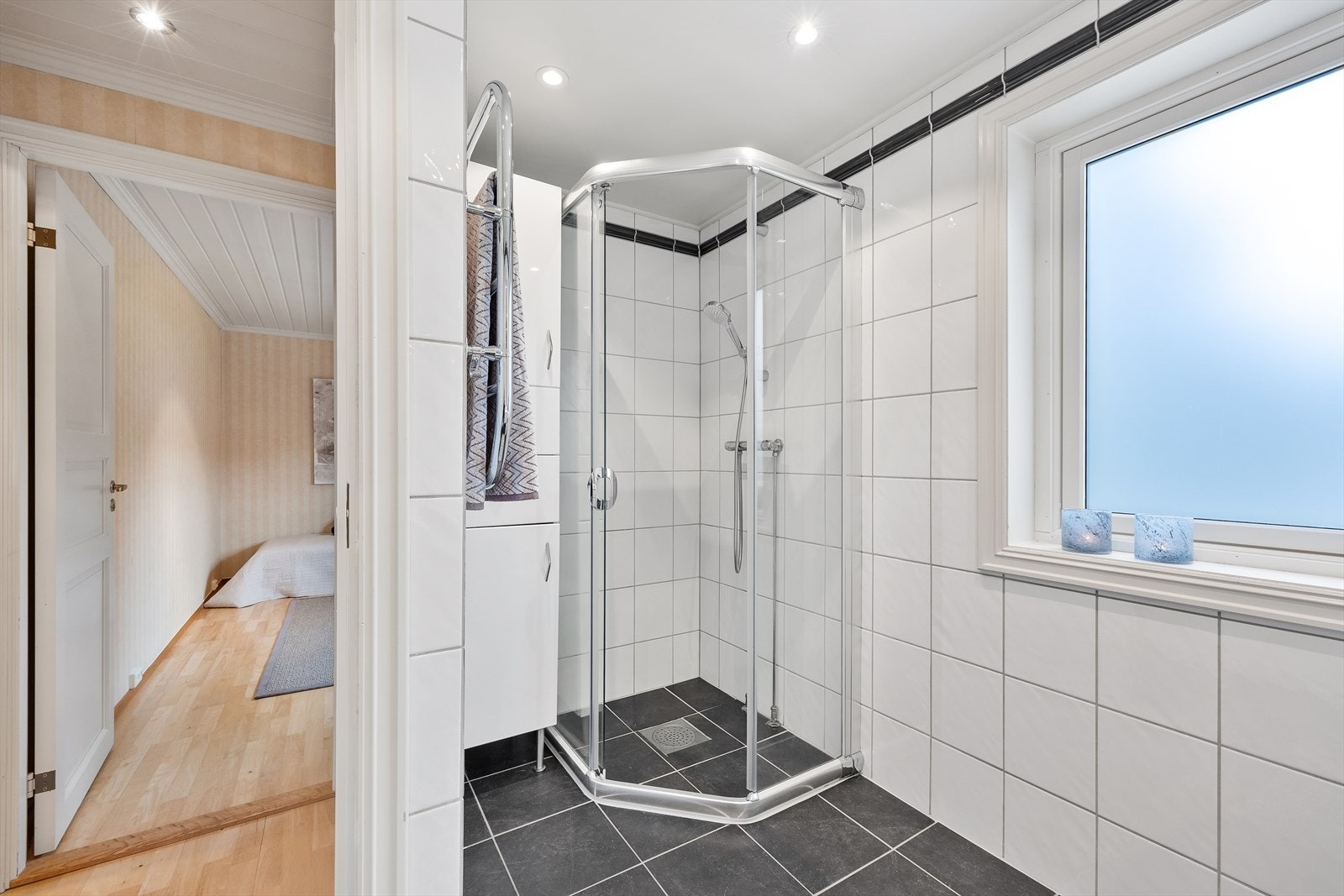 Badet er utstyrt med dusjhjørne med skyvedør, vegghengt wc og servantinnredning med skuffer. Galleribilde