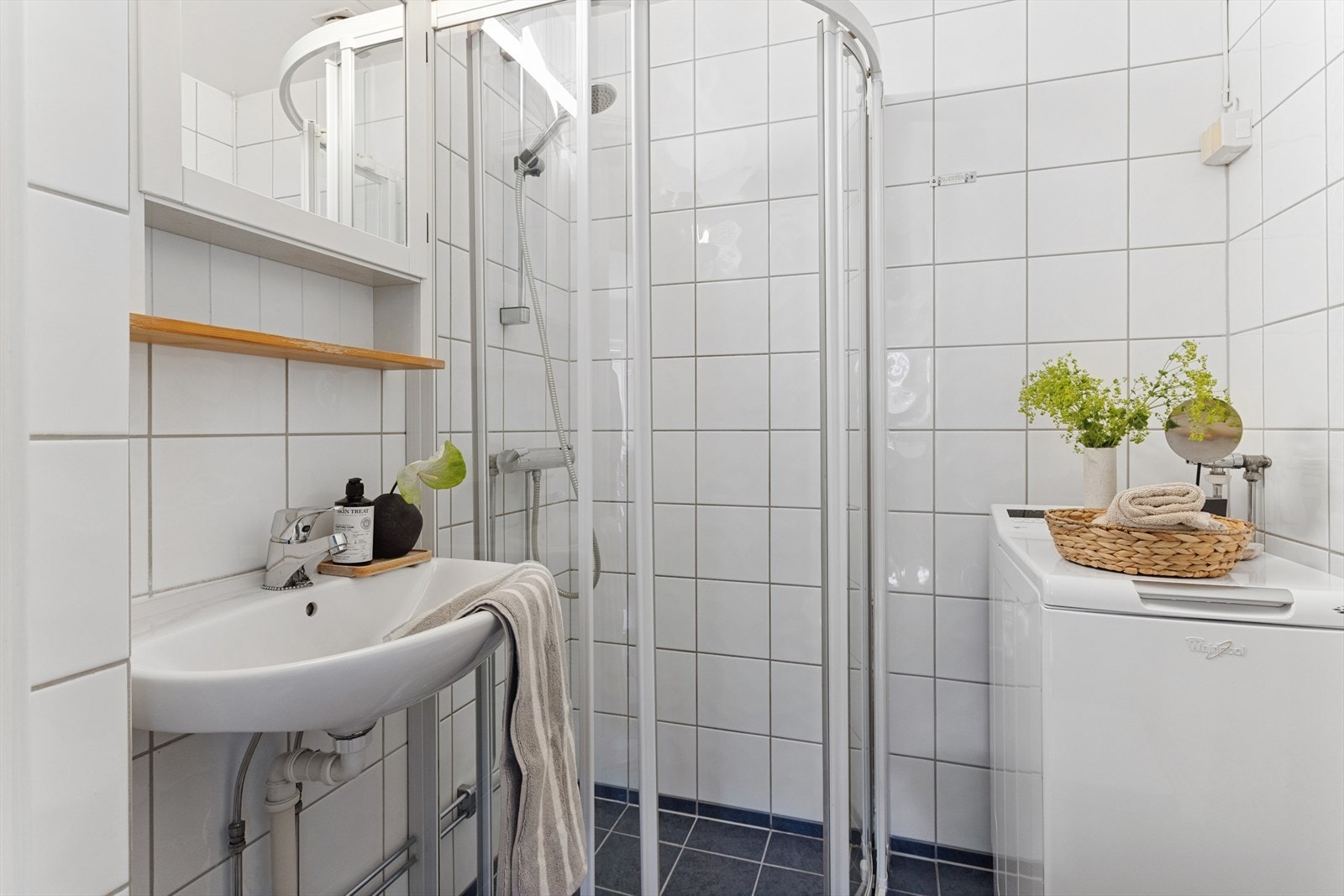 Badet består av servant, veggskap med speilfront, gulvmontert toalett og dusjhjørne med skyvedører. Galleribilde