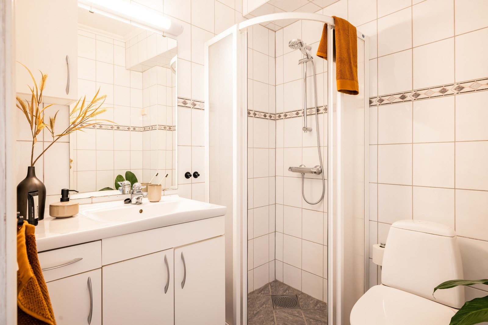 Badet er pent og helfliset i nøytrale fargevalg, det er varmekabler i gulvet og mekanisk avsug Galleribilde