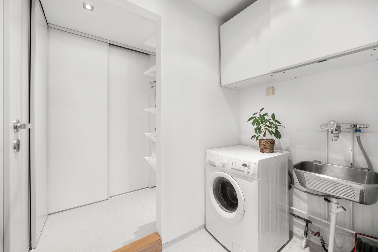 Vaskerommet innenfor kjøkkenet er praktisk med utslagsvask, hvite overskap og opplegg for vaskemaskin. Det er bod med hyller og god lagringsplass i to skyvedørsgarderober. Begge rom har gulvbelegg, hvite vegger og downlights i taket. Galleribilde