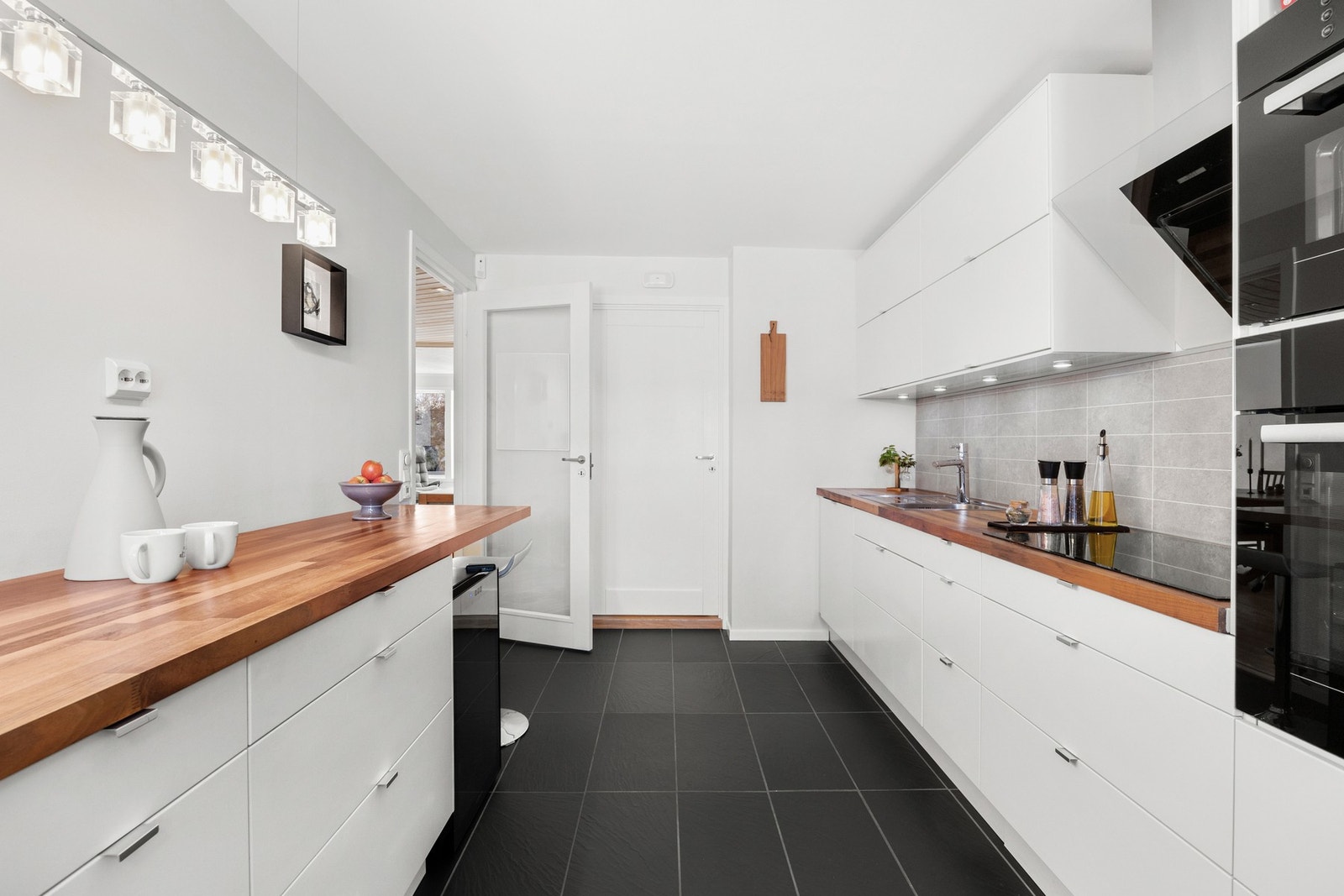 Det er integrert stekeovn og mikrobølgeovn i høyskap, samt oppvaskmaskin. Det er avsatt plass til kjøleskap. Veggene har listefri overgang til himling og er malt i fargen Frostrøyk, mens gulvet har sorte fliser med varmekabler Galleribilde