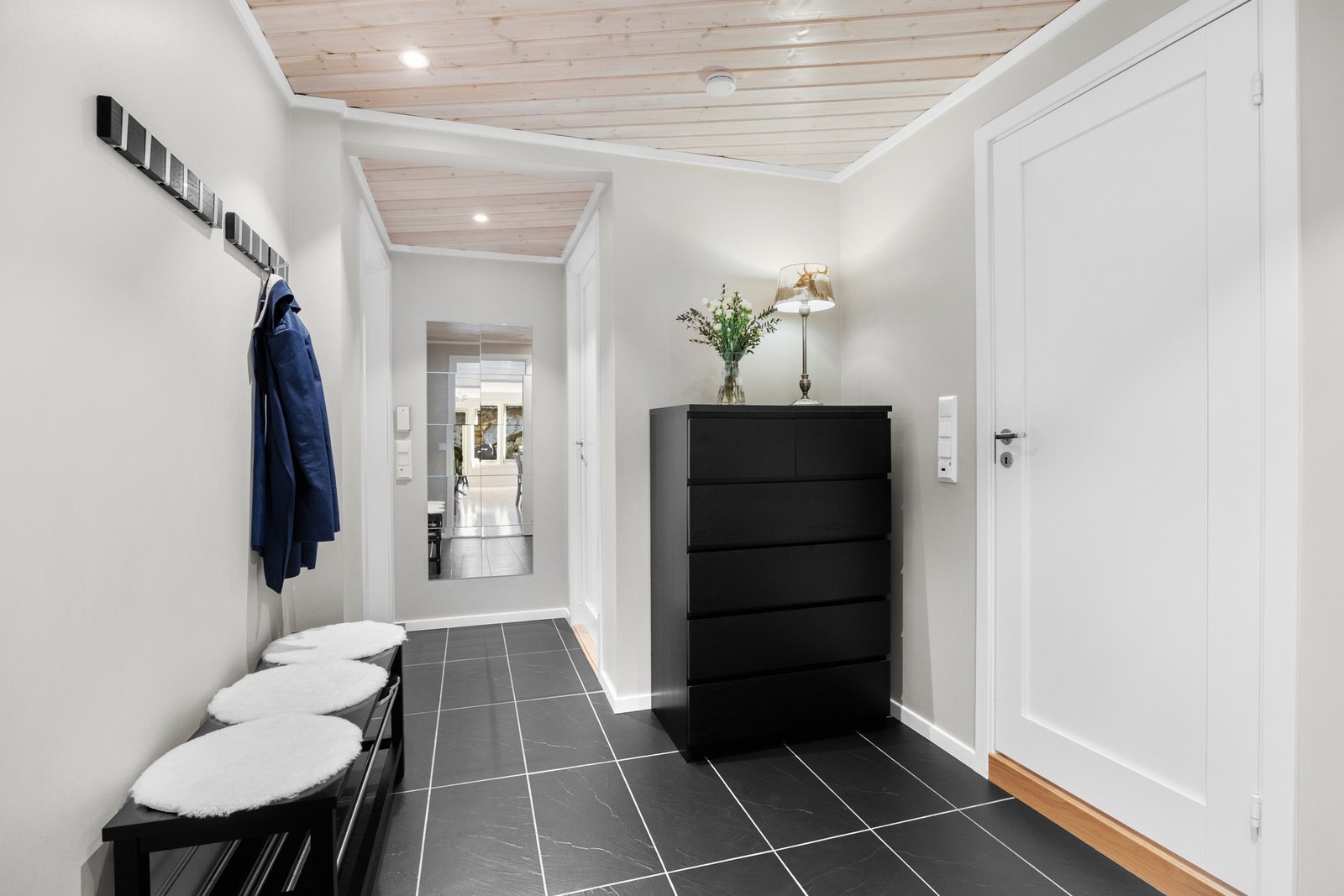 Vell inn dørstokken møtes du av en lys entré med flislagt gulv m/ varmekabler og slette veggfelter. I taket er det hvitvasket panel med innfelte downlights, som kan kontrolleres med smartstyring på mobil. Galleribilde