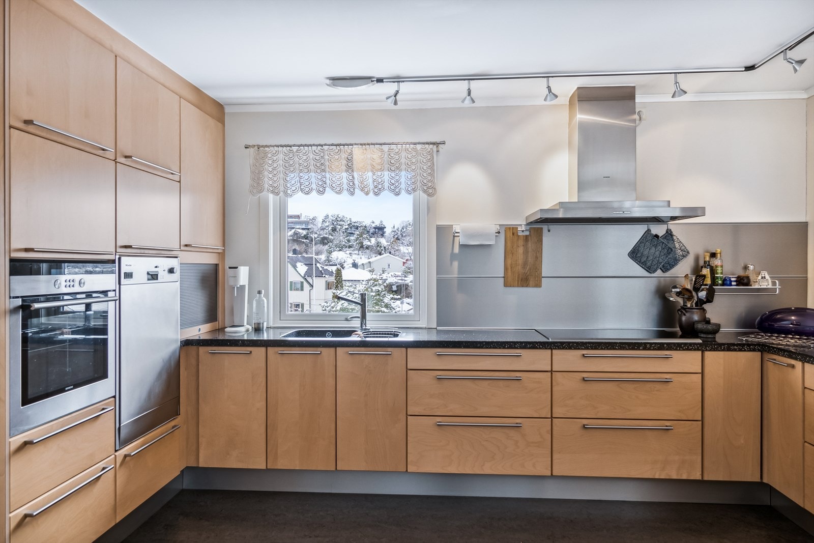 Deilig med oppvaskmaskin i ståhøyde. Fronter av finert heltre, benkplate av Corian komposittmateriale. Galleribilde
