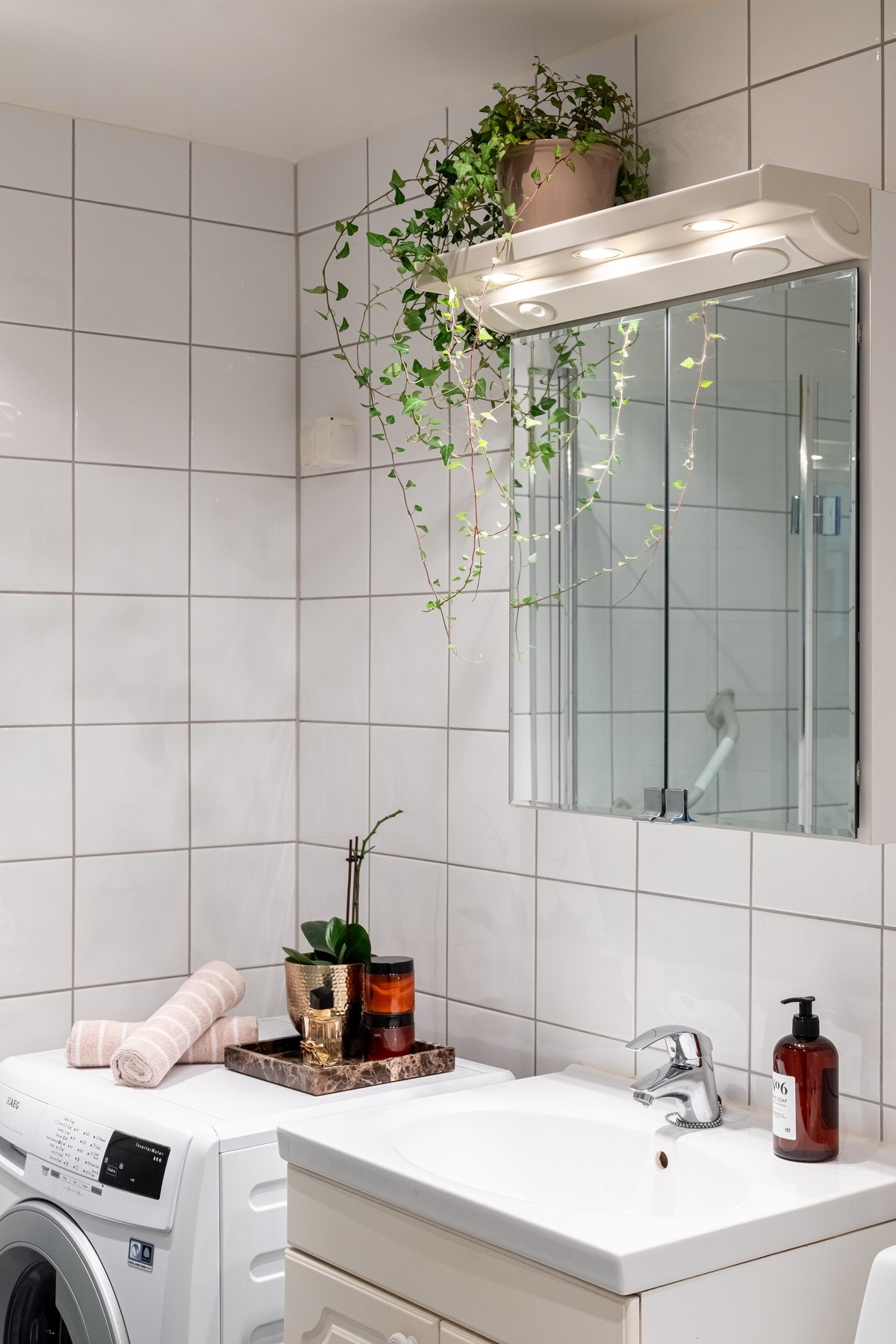 Det er et speilskap over med belysning og integrert stikkontakt. Videre på badet er det dusjhjørne med innfellbare glassdører og toalett. Det er også opplegg for vaskemaskin. Galleribilde