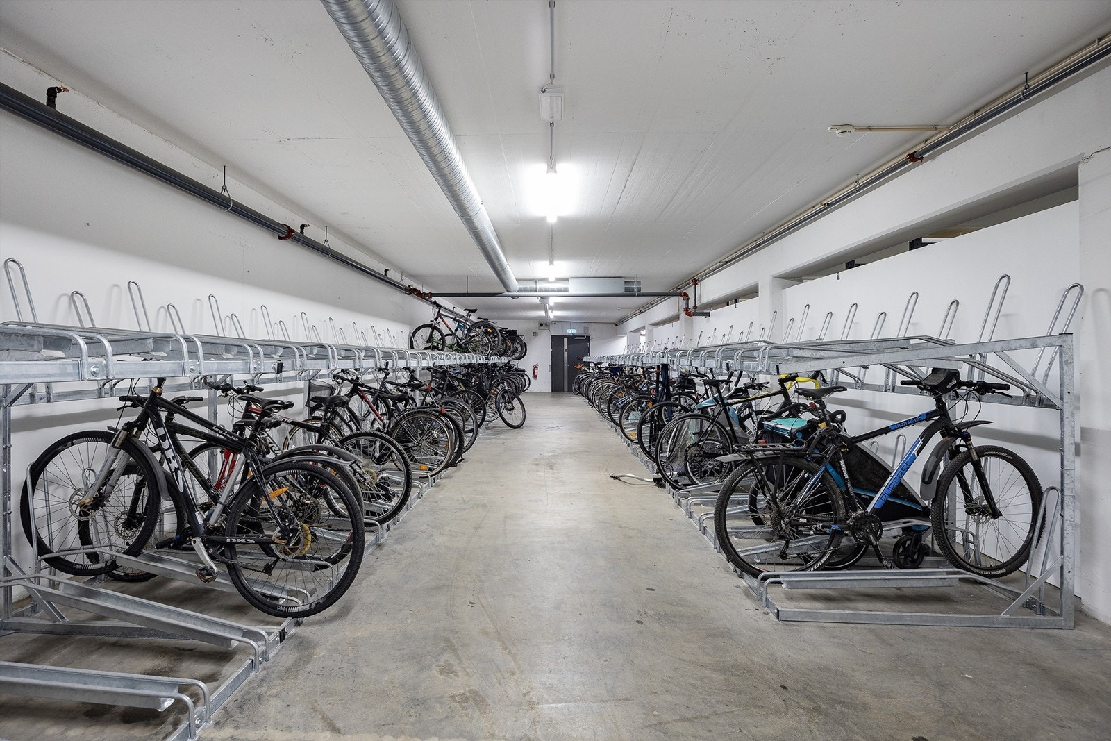 Stor sykkelparkering for ca. 500 sykler, sykkelvask & sykkelreparasjons stasjon og bord for skismøring i kjeller Galleribilde