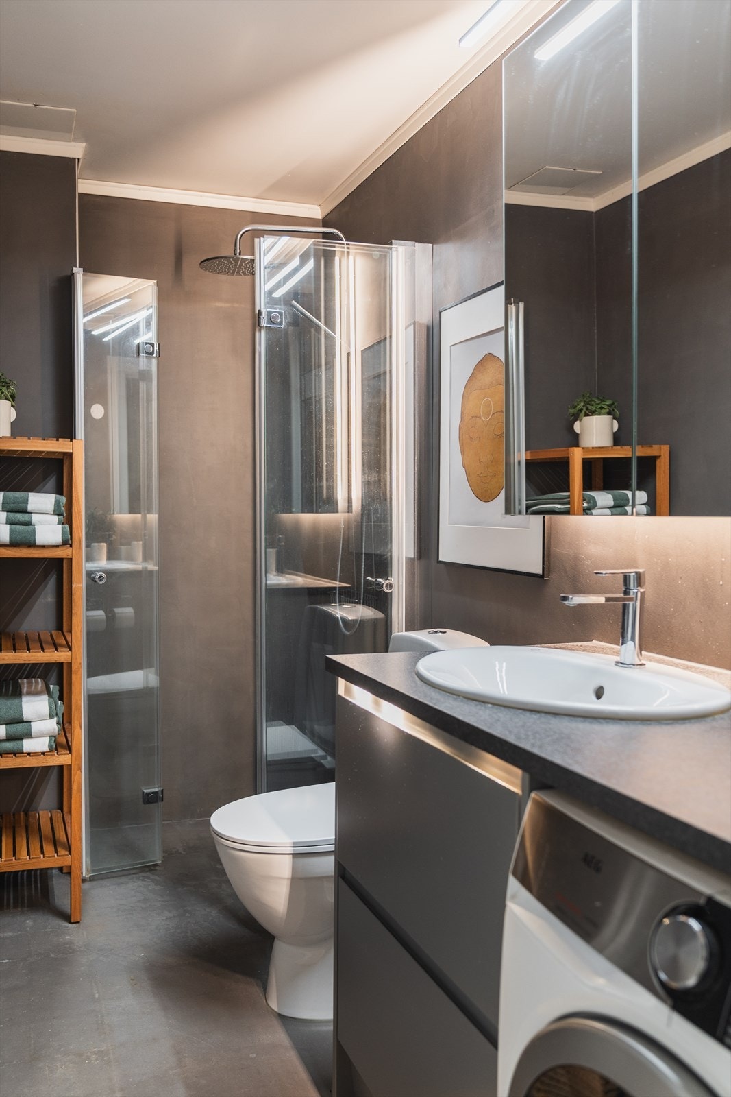 Baderommet er utstyrt med toalett, servant med innredning, dusj med innfellbare dører i herdet glass og opplegg for vaskemaskin Galleribilde