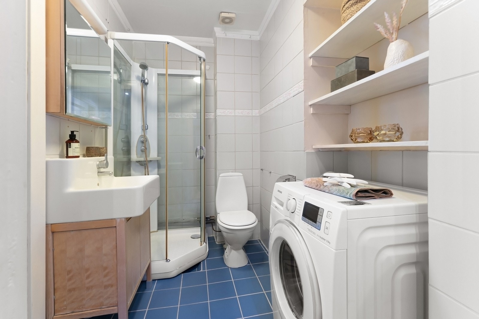 Av innredning har badet servant, gulvmontert toalett, dusjkabinett og opplegg for vaskemaskin. Det er mekanisk avtrekk til felles luftekanal. Galleribilde