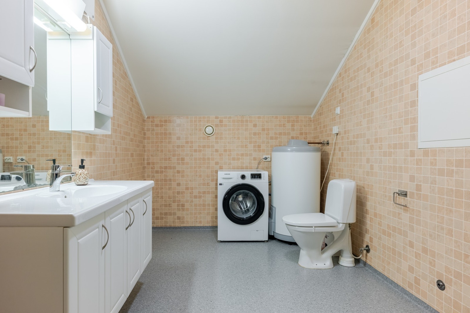 Romslig bad/vaskerom med nedfelt servant, toalett, dusjkabinett og opplegg for vaskemaskin. Galleribilde