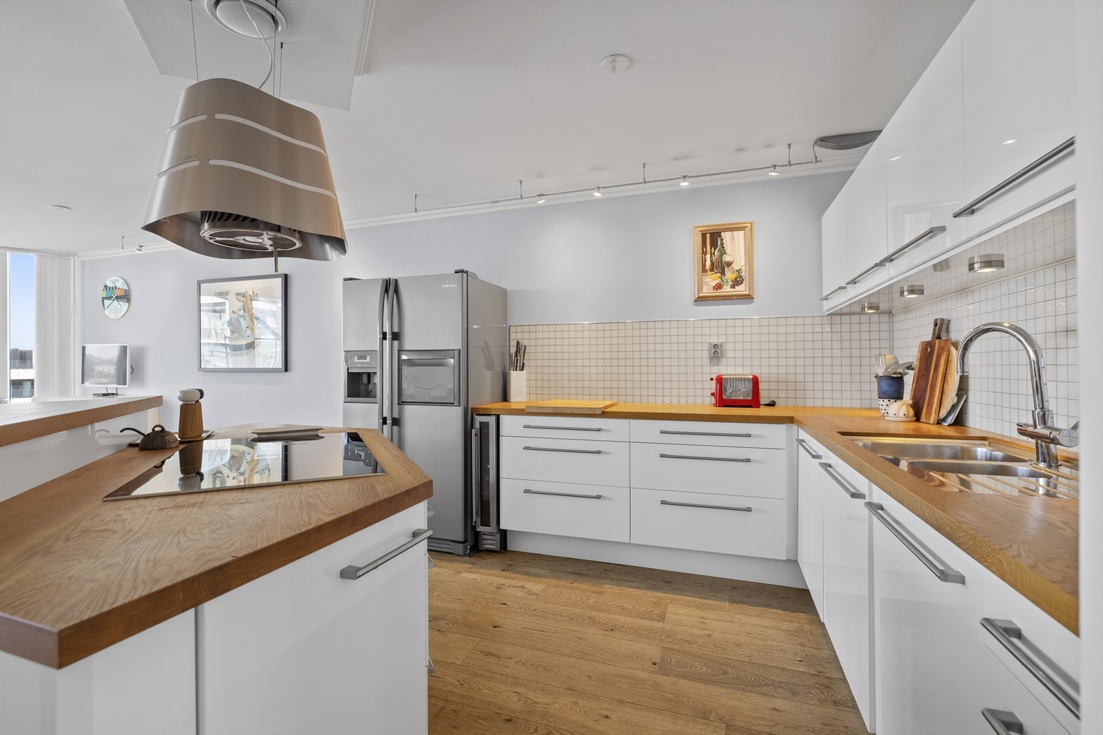 Kjøkkenet har hvite glatte fronter og tre benkeplate. Det er godt med skapplass. Galleribilde