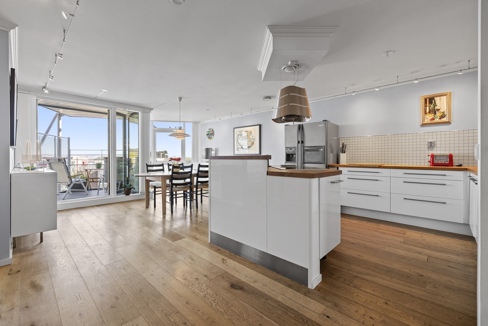 Kjøkken med spiseplass og doble dører ut til balkong med morgensol. Galleribilde