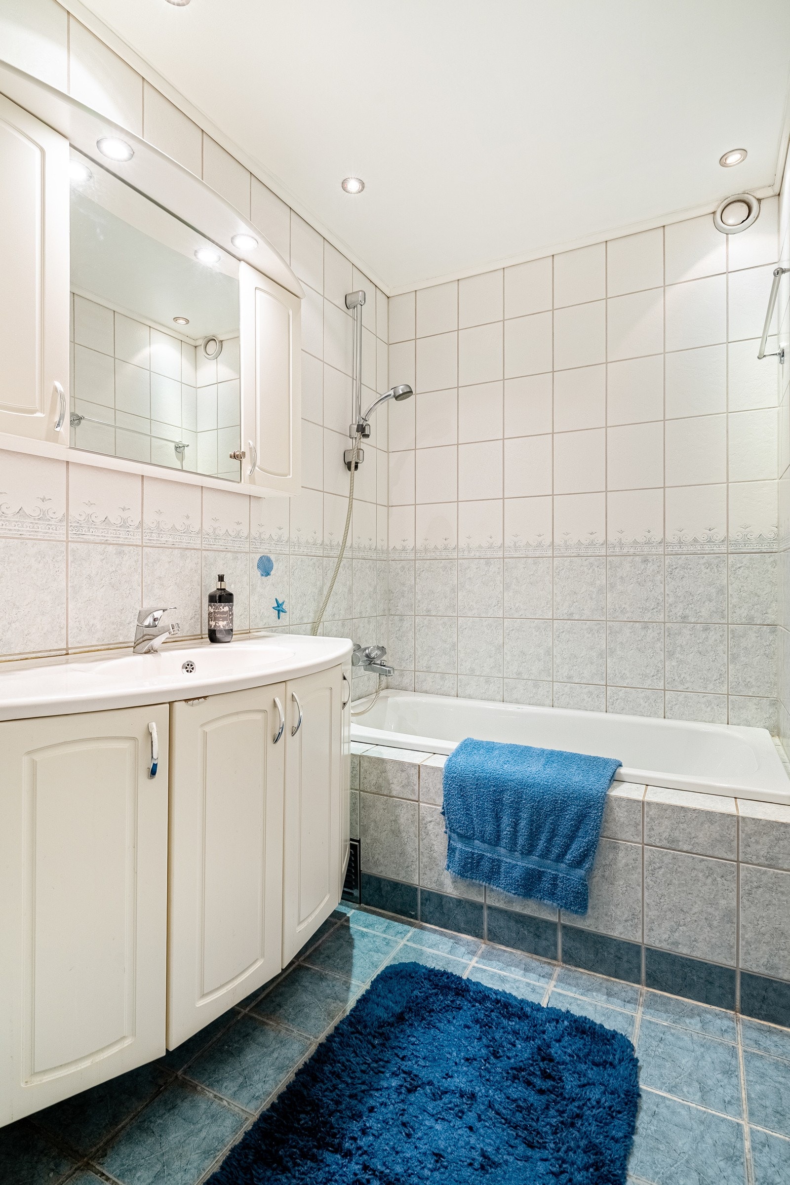 Flislagt bad med varmekabler i gulv og downlights i himling. Badet er utstyrt med servant i en lys baderomsinnredning og innebygd badekar. Galleribilde