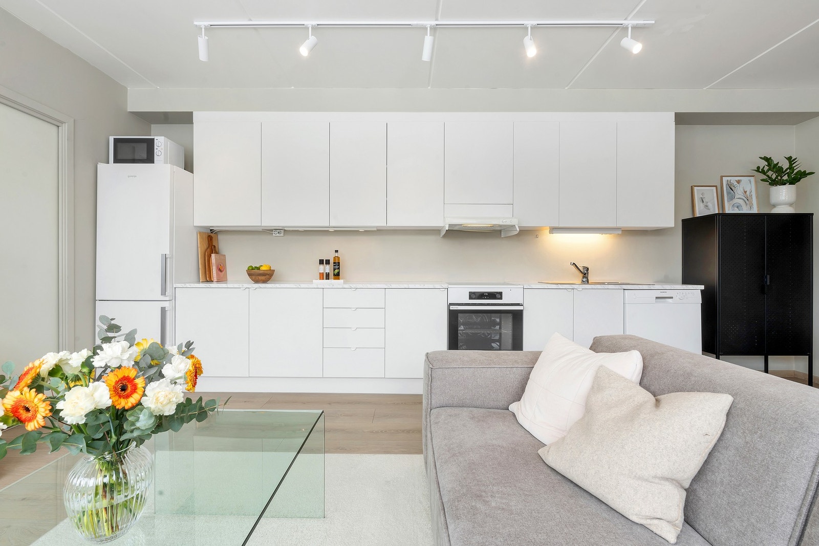 Moderne kjøkken innredet med hvite glatte fronter, benkeplate i laminat, frittstående komfyr og kjøleskap med fryser. Galleribilde