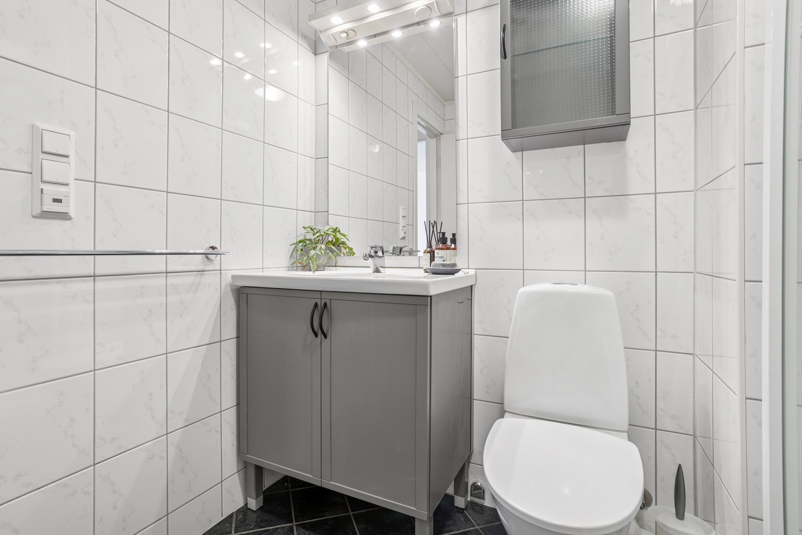 Innredning med nedfelt servant, speil over vask, gulvstående toalett, dusjkabinett og opplegg for vaskemaskin. Galleribilde