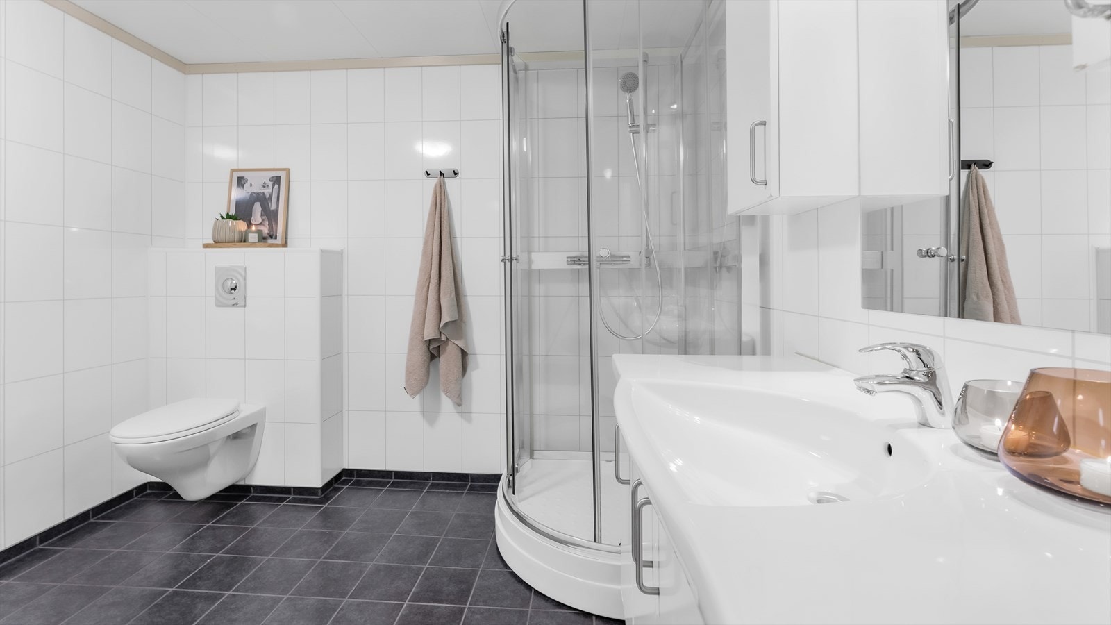 Badet er utstyrt med baderomsinnredning, vegghengt wc og dusjkabinett. Galleribilde