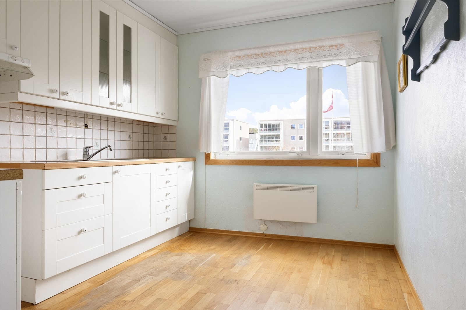 Kjøkkenet måler 9,1 m² og har eldre innredning med hvite fronter og laminert benkeplate med kjøkkenbeslag. Galleribilde