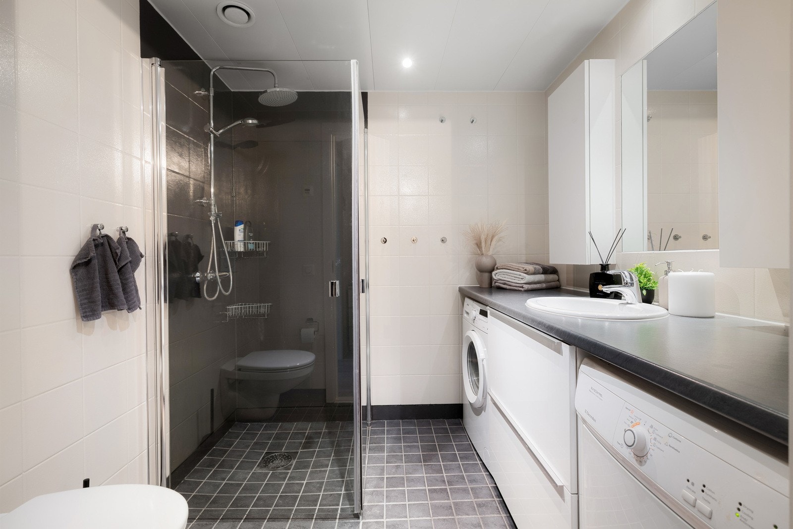 Lyst og romslig baderom med nedsenket dusjhjørne med svingdører i glass. Galleribilde