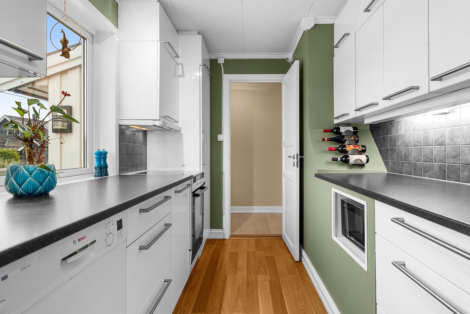 Kjøkkeninnredning fra 2011. Gulvflate belagt med laminat. Veggflater med malte flater. Himlingsflate med hvite himlingsplater. Kjøkken med høyglans fronter. Benkeplater av laminat. Galleribilde