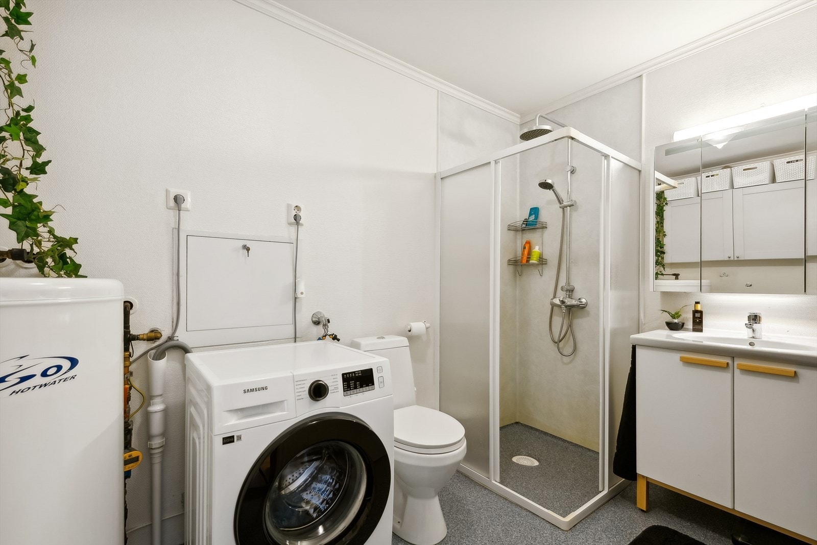 Badet er innredet med servant, toalett og en hjørnedusj. Det er og opplegg til en vaskemaskin Galleribilde