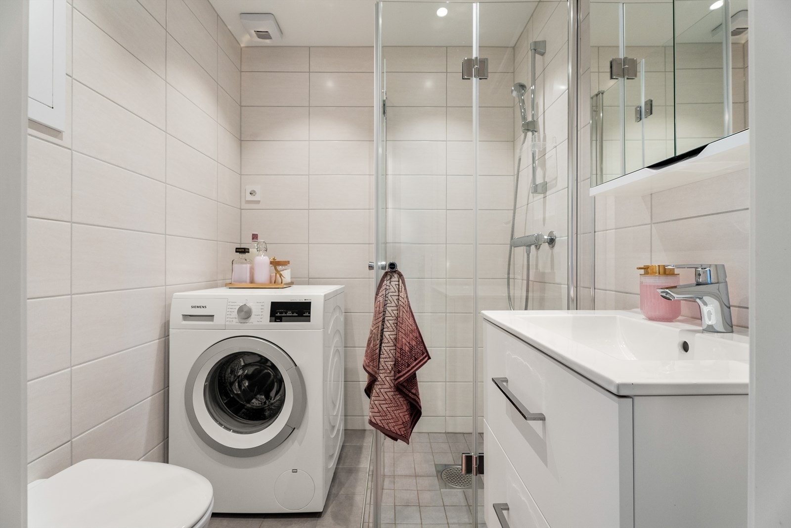 Baderommet har flislagte gulv- og vegger og malt gips i himling. Baderommet er utstyrt med dusjhjørne med innfellbare glassdører, stilig skuffinnredning med nedfelt servant samt speilskap over. Galleribilde