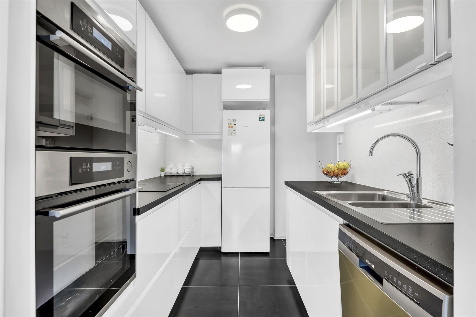 Kjøkkeninnredning fra IKEA med slette høyglans fronter og laminat benkeplate med fliser på bakvegg. Galleribilde