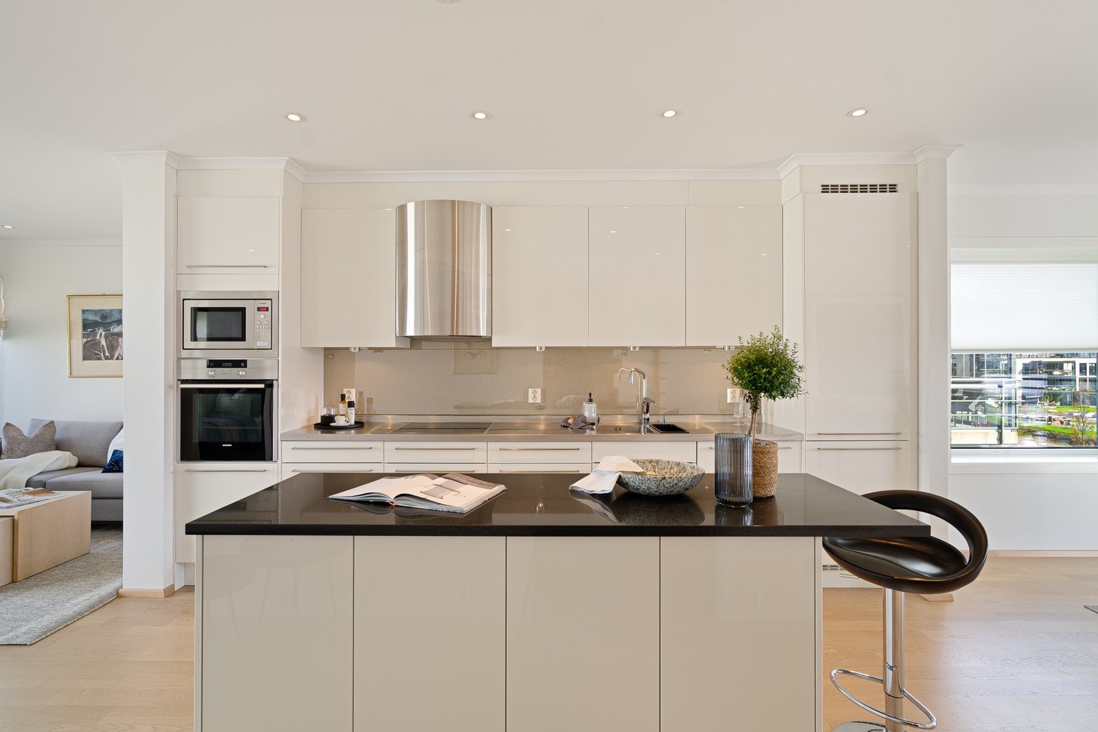 Lekkert kjøkken med integrerte hvitevarer og praktisk kjøkkenøy Galleribilde