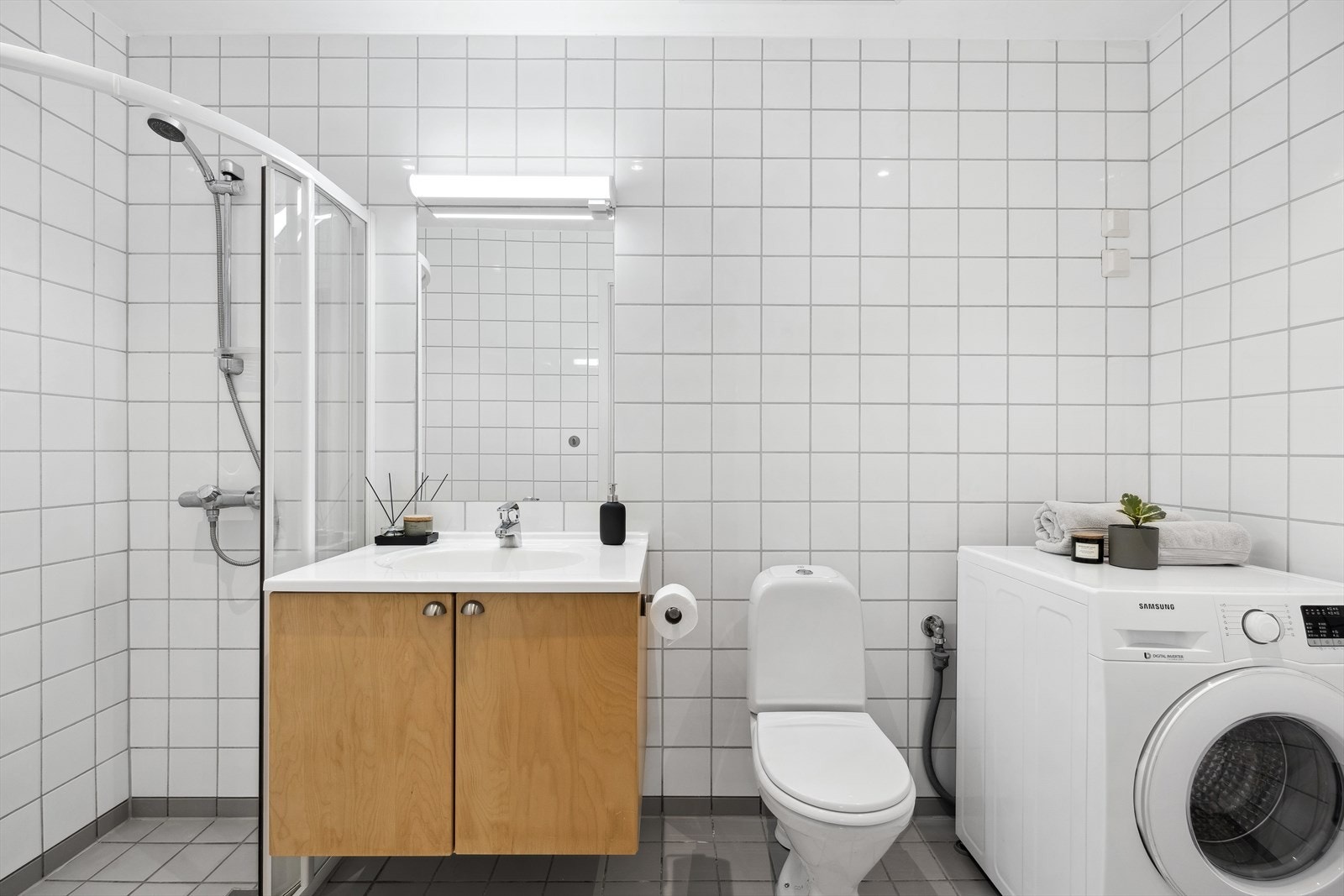 Lyst og tidløst baderom med varmekabler i gulv og opplegg for vaskemaskin. Galleribilde