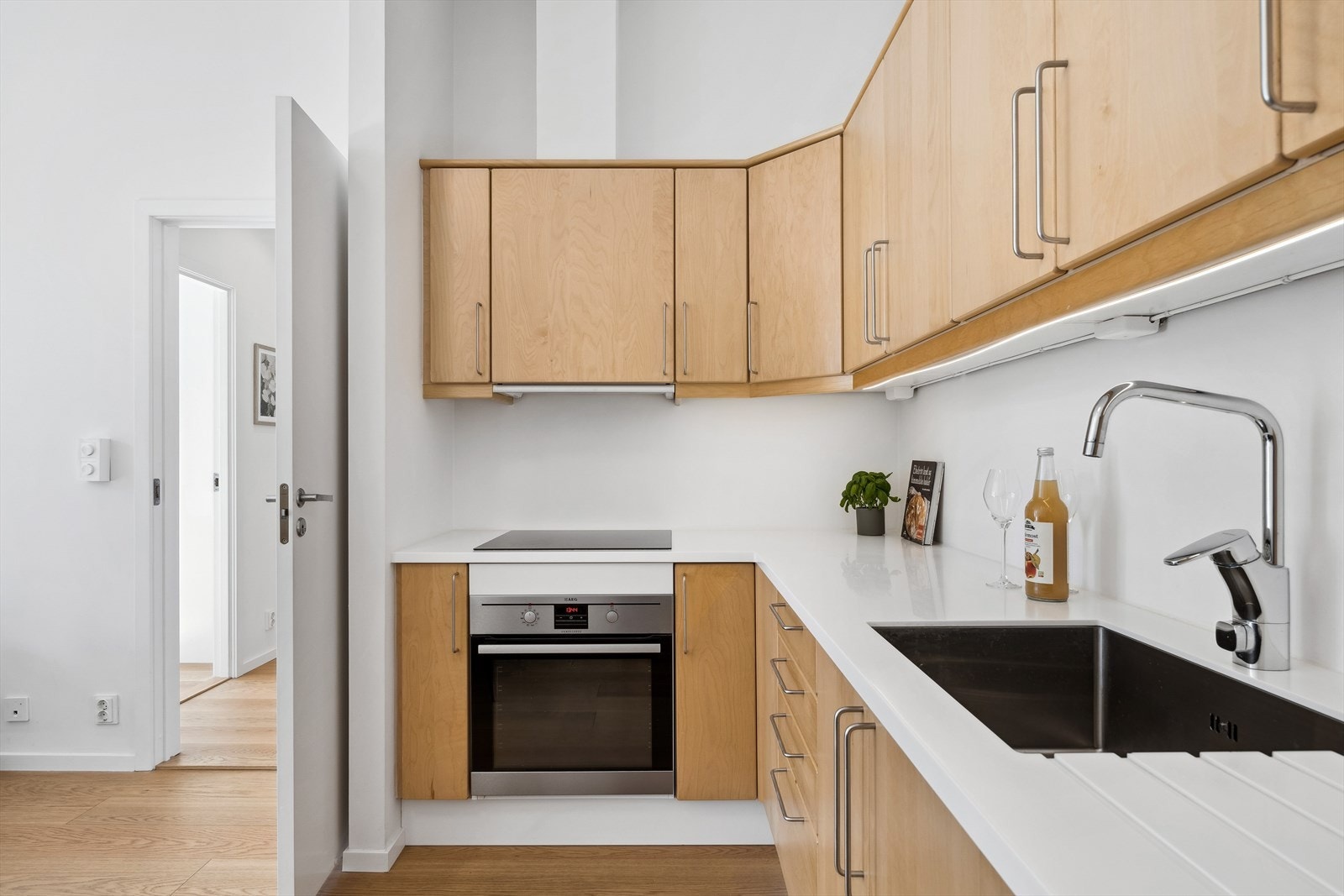 Lys og tidløst kjøkken. Dette er oppgradert de senere år med ny stekeovn og koketopp fra AEG, integrert oppvaskmaskin og Corian benkeplate med vask i 2017/18. Lys-list med dimmer under kjøkkenskap, ny i 2023. Galleribilde