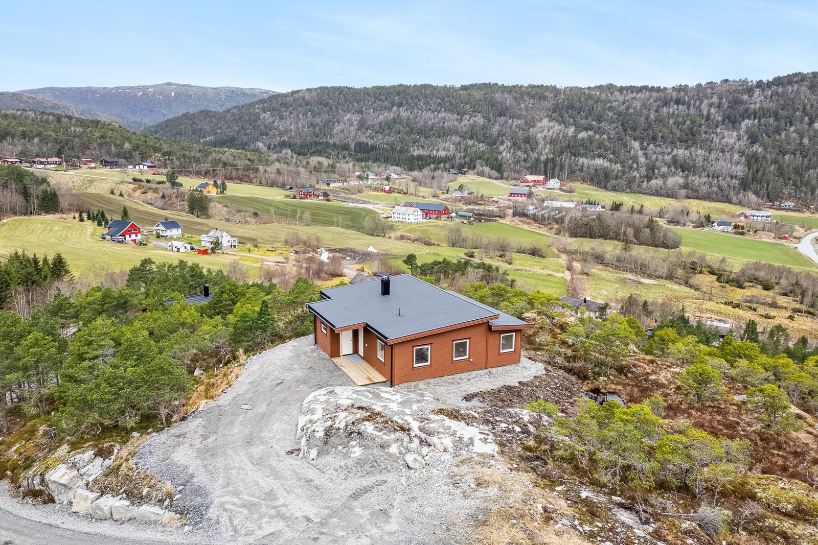 Naturtomt opparbeidet med grus, platting på terreng og biloppstillingsplass. Galleribilde