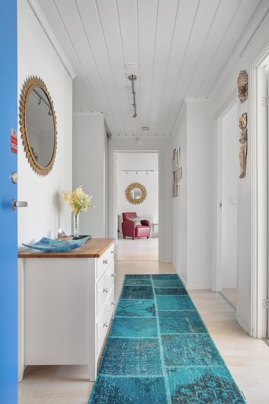 Romslig gang med parkettgulv, malte veggflater og skyvedørsgarderobe Galleribilde