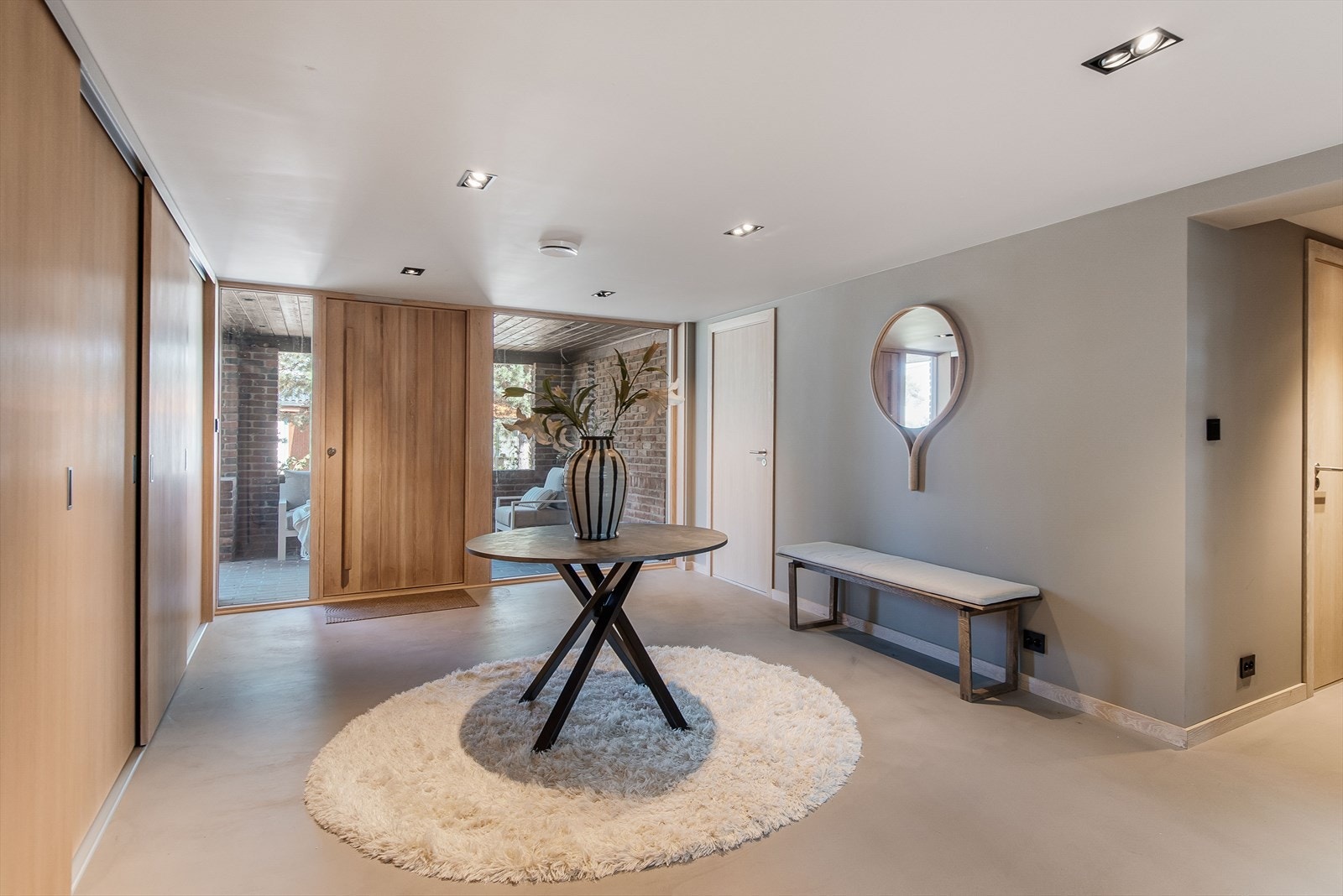 Boligens entré leder til en stor, lys hall med stilig mikrosement på gulv. Galleribilde