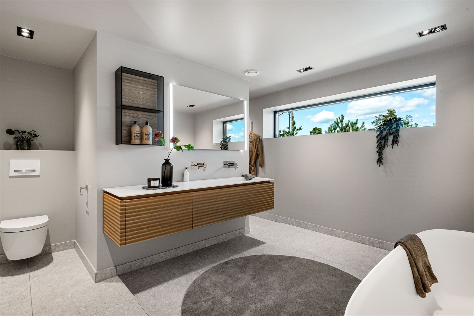 Hovedbadet kombinerer funksjonalitet med velvære, med detaljer som servantskap i trefinish med to servanter og et frittstående badekar. Galleribilde