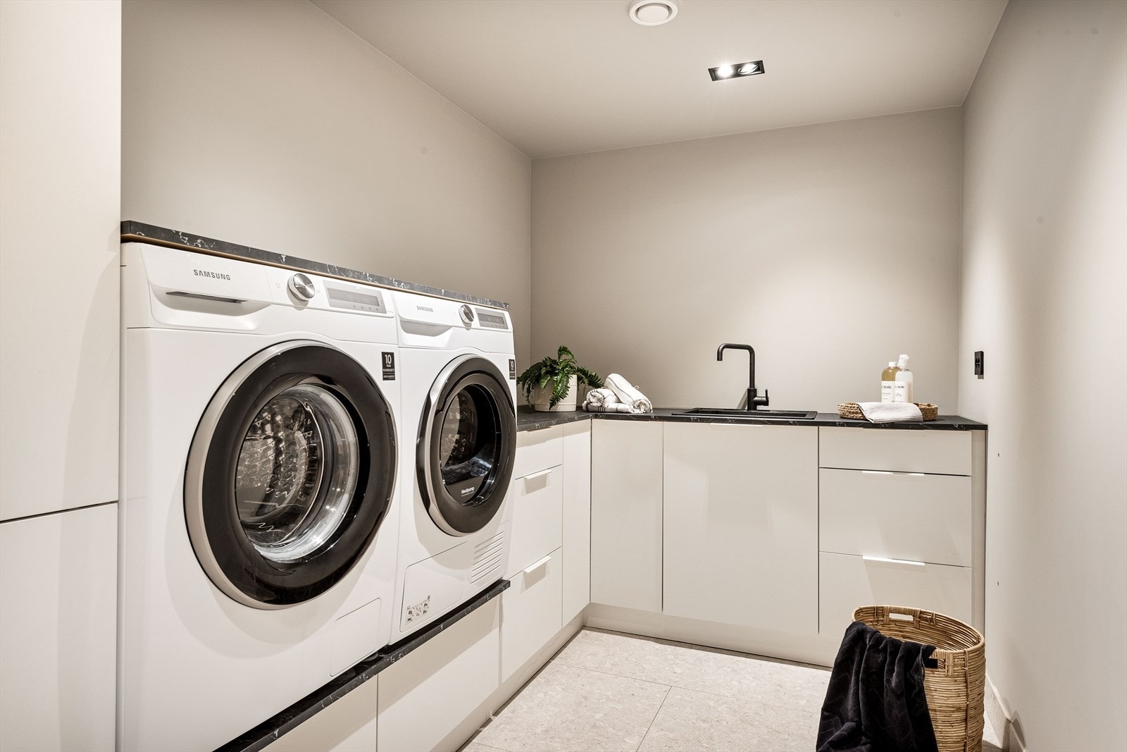 Rommet har flislagt gulv og er innredet med skap, skuffer og benkeplate med nedfelt servant, samt nisje for vaskemaskin og tørketrommel. Galleribilde