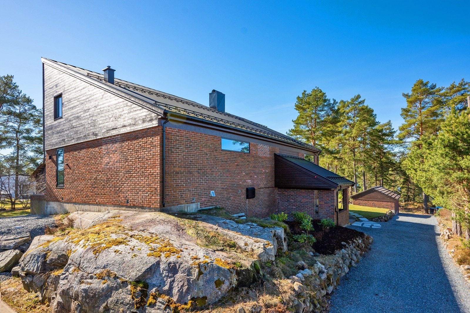 Det er gruslagt gårdsplass med elbil lader på veggen Galleribilde