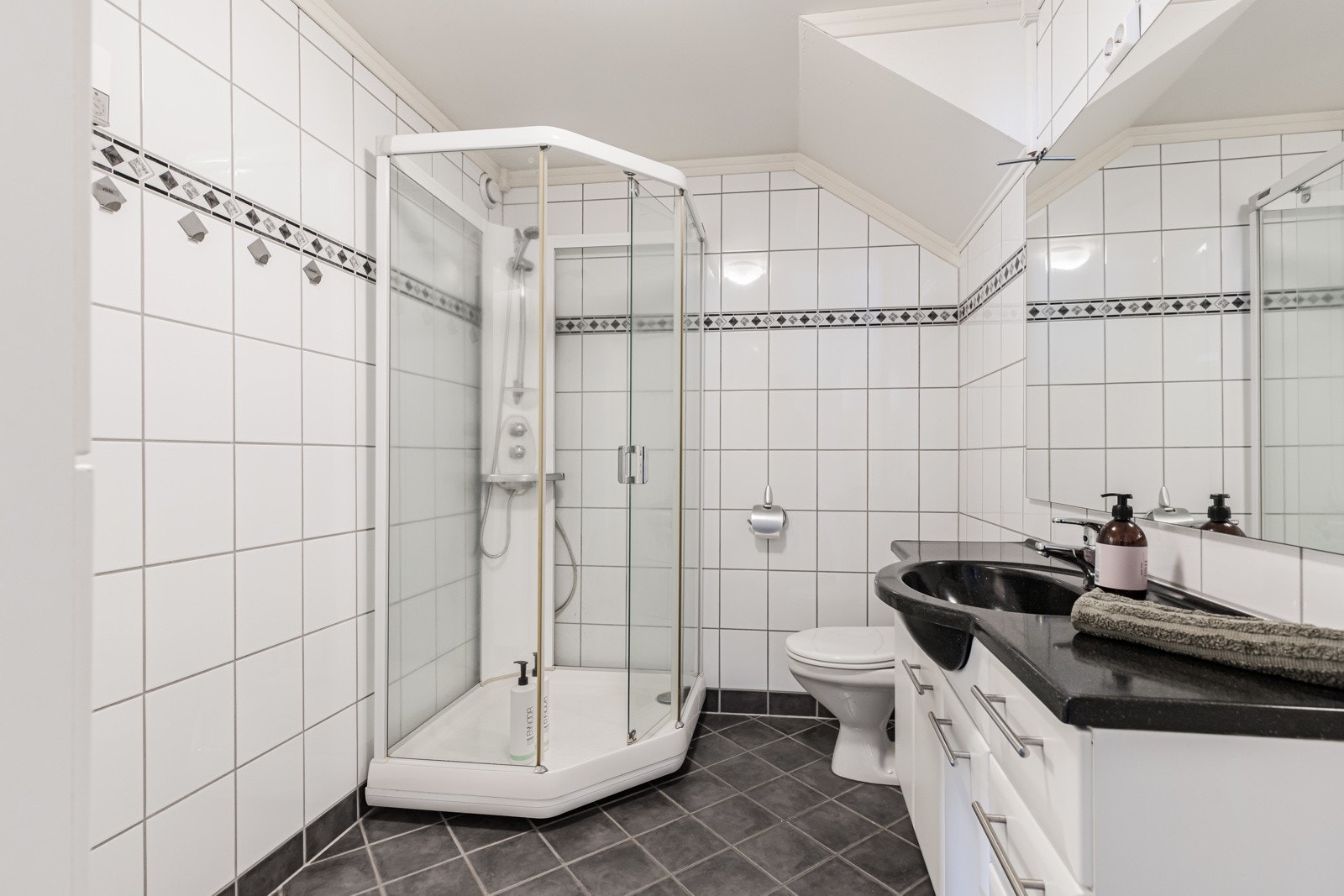 Badet ble pusset opp i 2006, innredet med hvite veggfliser og mørke gulvfliser for en fin kontrast. Galleribilde