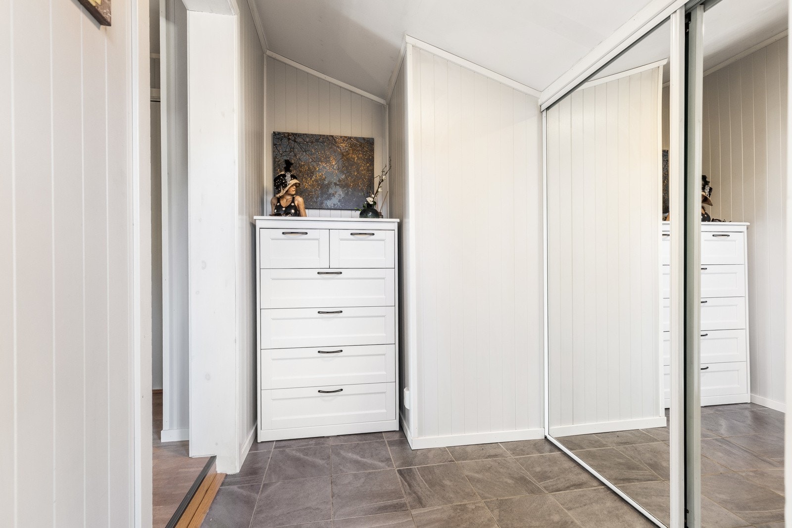 Vel inne har entreen varme under grå fliser på gulvet, og yttertøyet ryddes enkelt bort i en stor og plassbygd skyvedørsgarderobe med speilfronter. Galleribilde