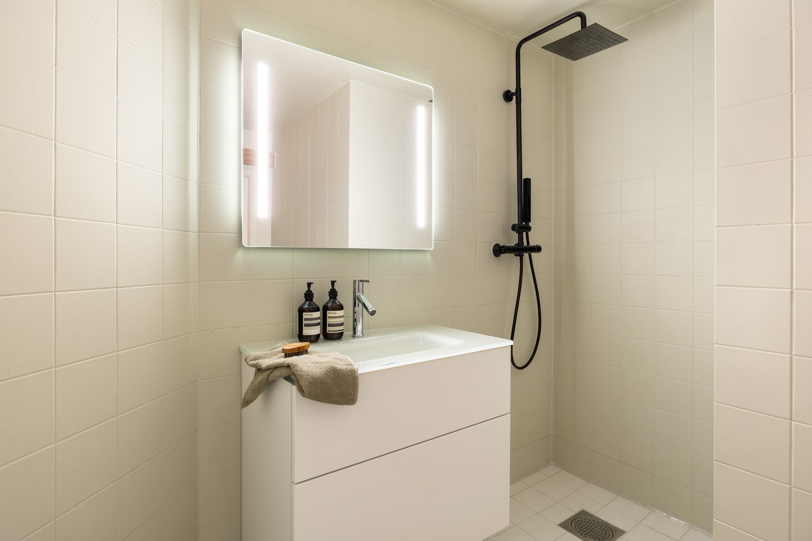 Badet er innredet med servantskap med glatte lyse fronter, heldekkende servant med ett-greps armatur, speil med belysning over servant, dusjnisje med dusjforheng, samt toalett. Galleribilde