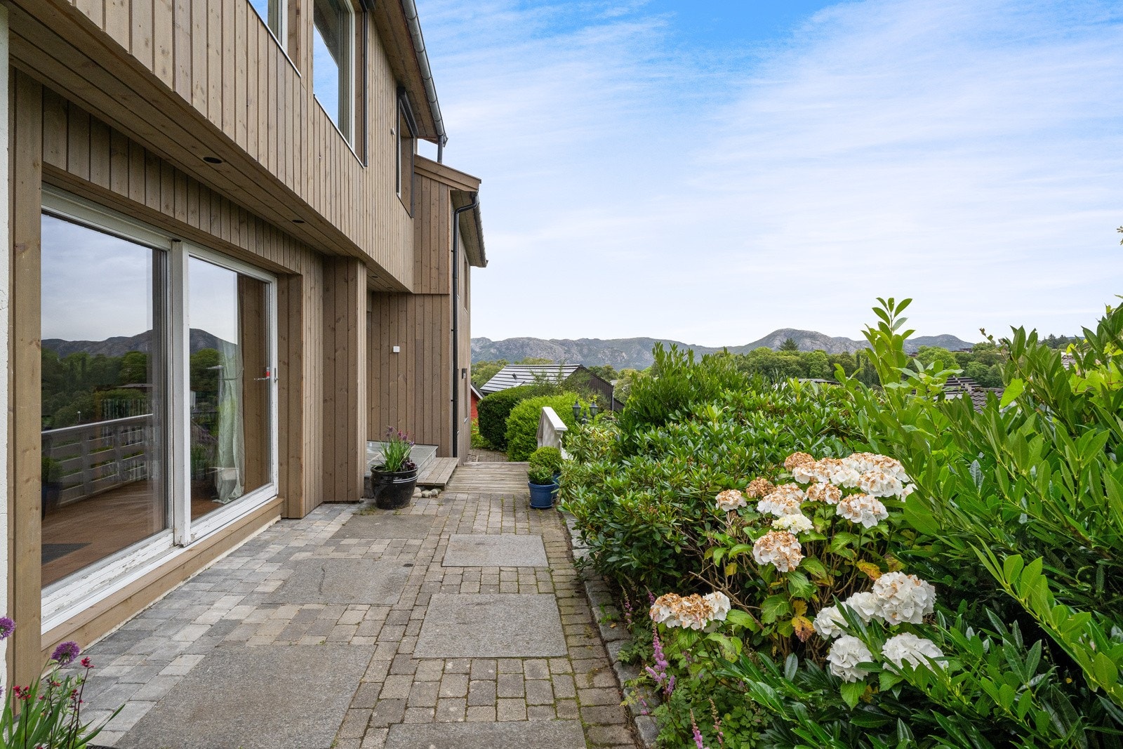 Boligen ligger fint plassert på en skrånende tomt med hagestue og koselige uteplasser. Galleribilde