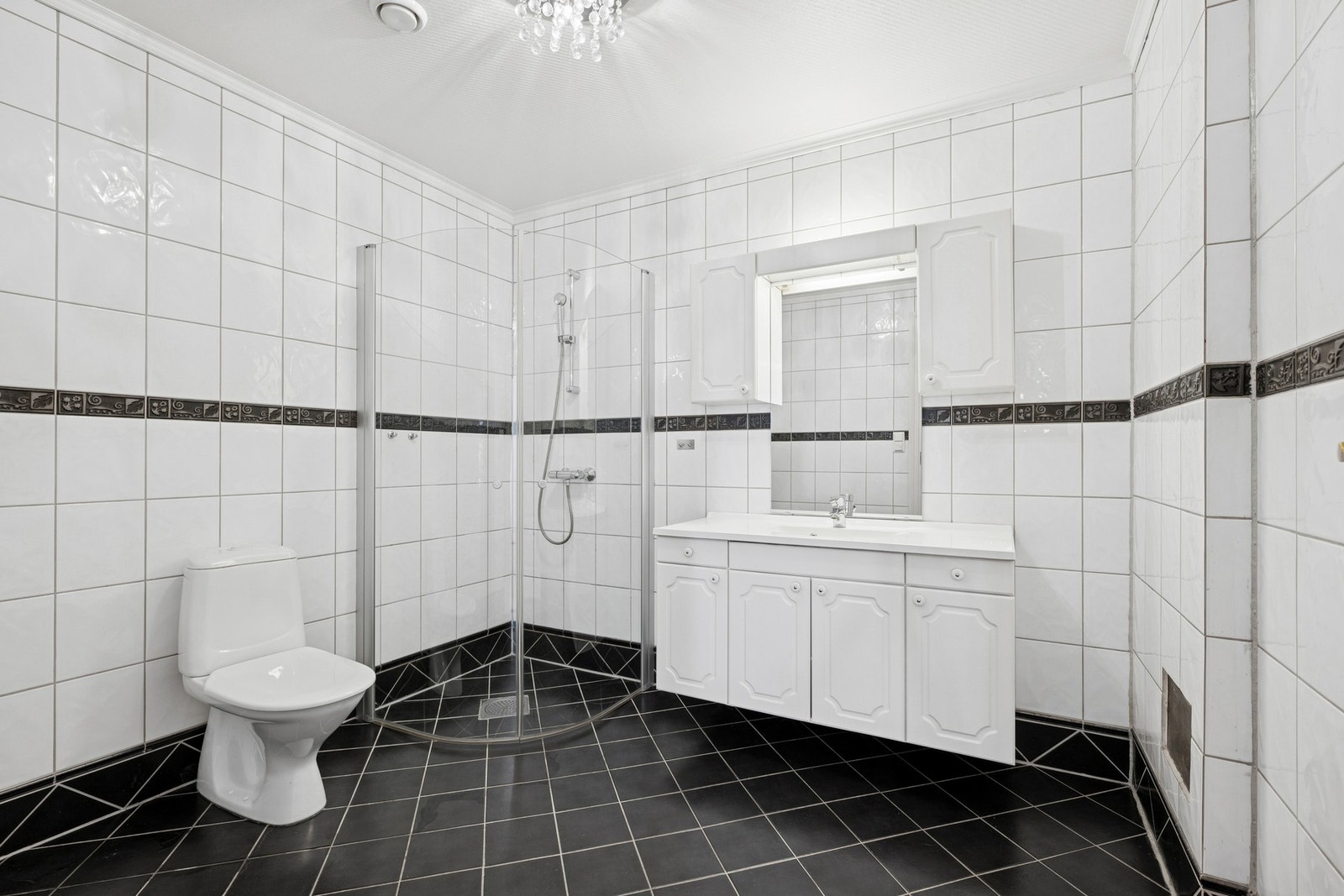 Romslig bad med tidløst preg. Badet har flislagt gulv med behagelig gulvvarme, og veggene er kledd med lyse fliser kombinert med dekorflis i kontrastfarge. Galleribilde