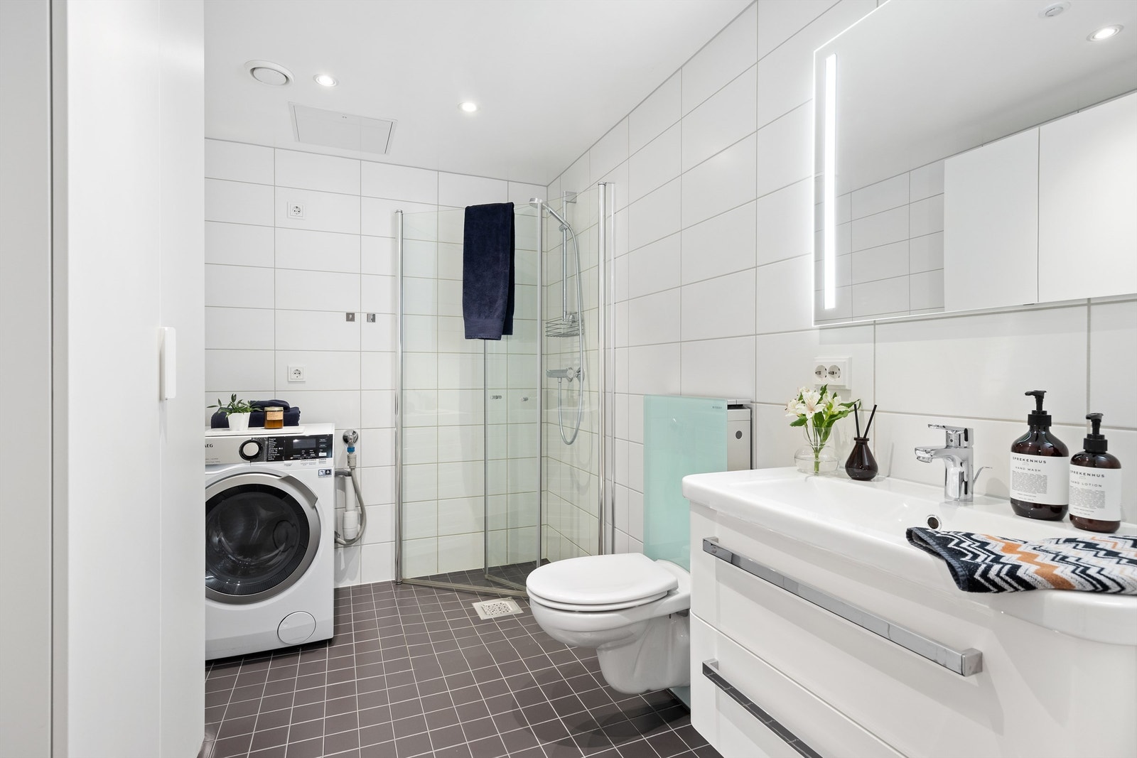 Innbydende og meget romslig bad med delikat flisvalg på gulv og vegg, varme i gulv samt downlights i nedsenket himling Galleribilde