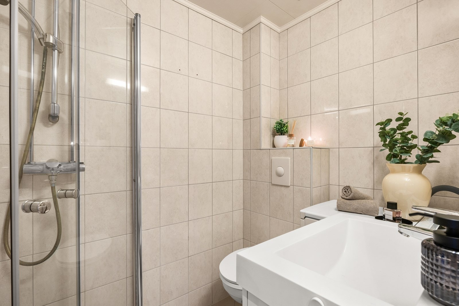 Badet har praktisk dusjhjørne, toalett, servant med innredning og opplegg for vaskemaskin Galleribilde