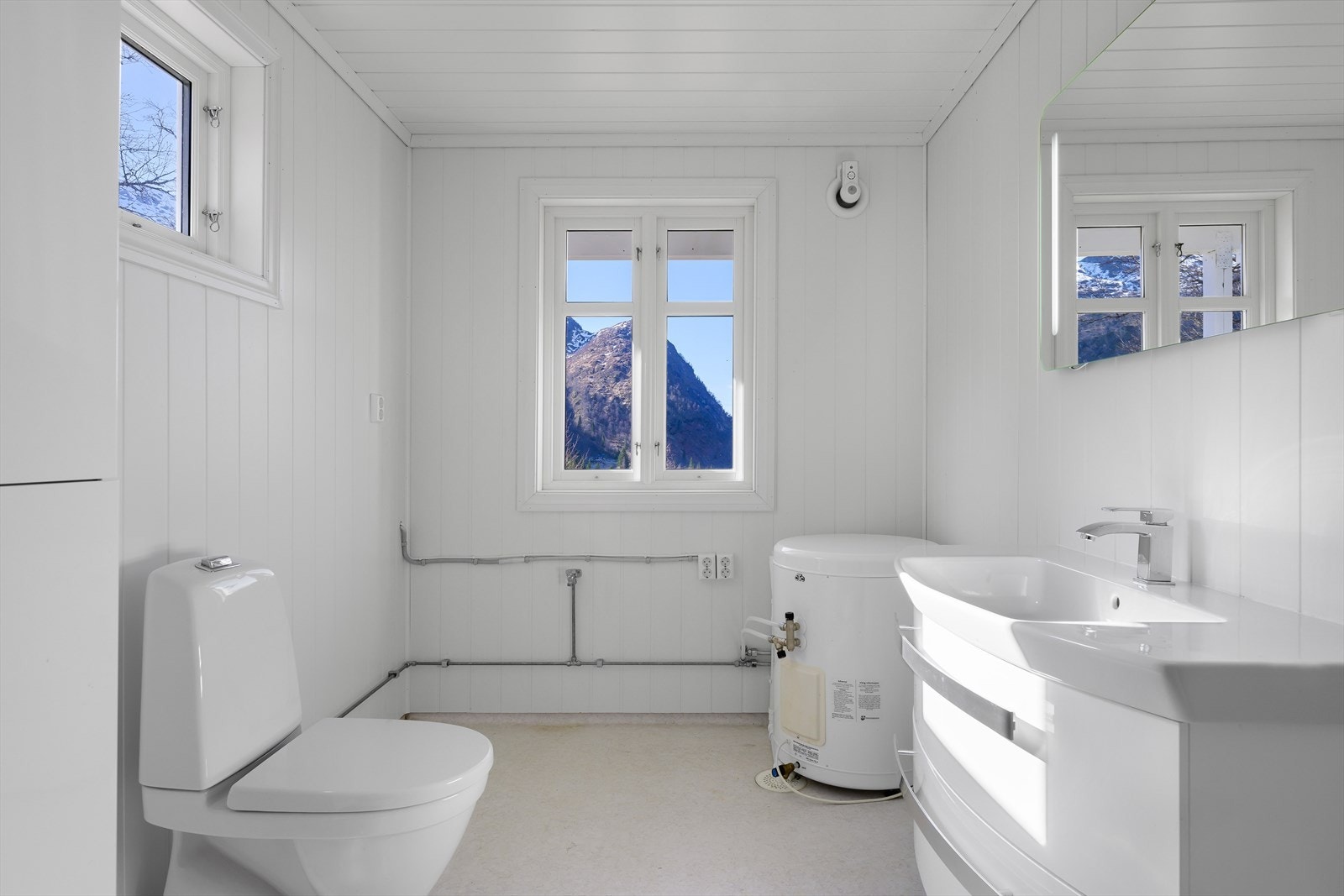 Badet er utstyrt med toalett, servant med speil, dusjkabinett og varmtvannstank. Galleribilde