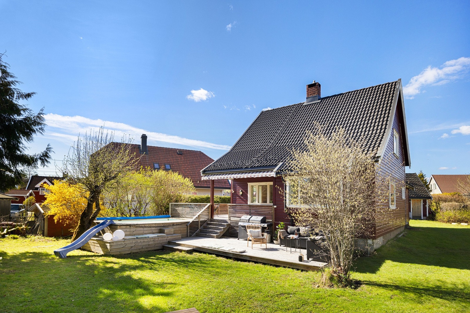 Tomten er solrik og pent opparbeidet med terrasse, plen og ulik beplantning Galleribilde