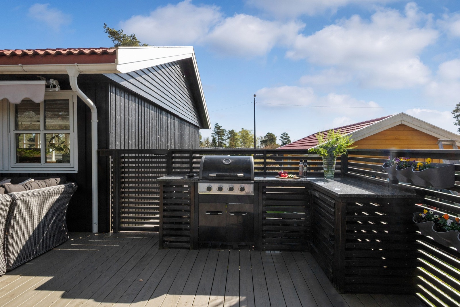 Sommerens matlaging blir enda hyggeligere med et praktisk utekjøkken i L-form. Kjøkkenet har steinbenk og egen nisje for grillen. Galleribilde