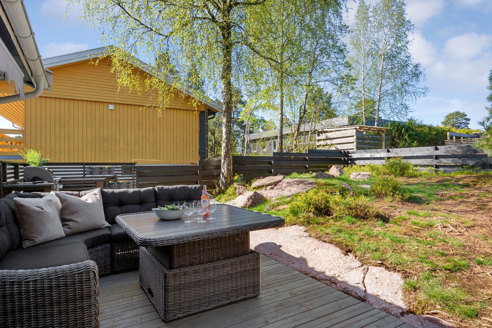 Eneboligen ligger på en romslig tomt, opparbeidet med plen, hekk, bed, busker, store trær og en lekestue til glede for de minste Galleribilde