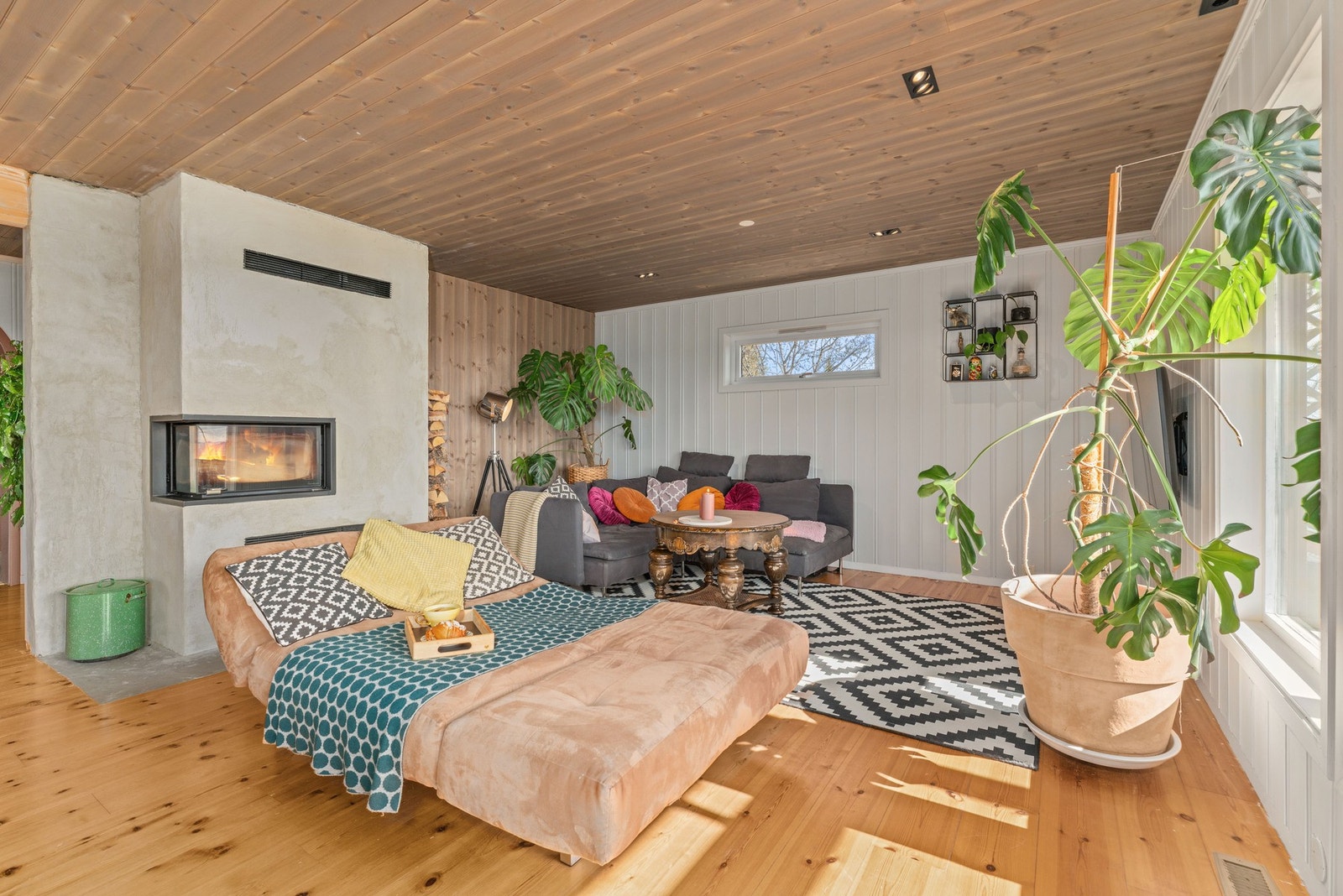 Nyere peisinnsats med pusset mur. I himling er det beiset panel samt endel downlights. Galleribilde