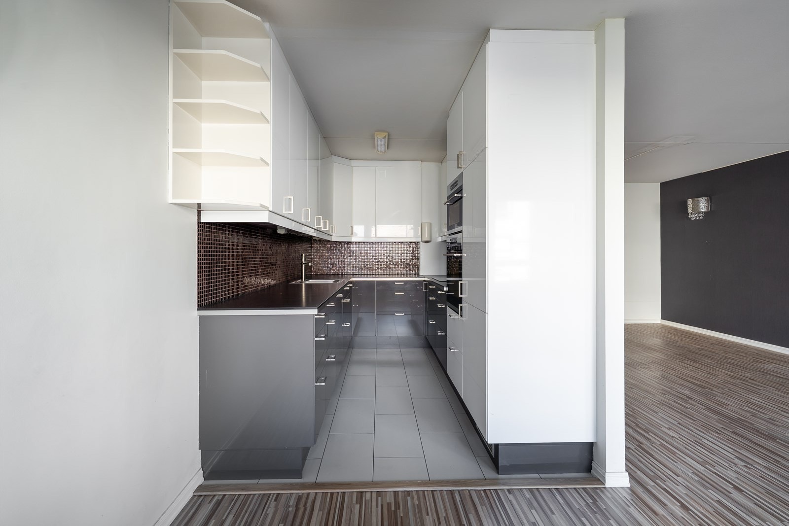 Innredningen har mørke laminatbenkeplater, grå underskap og hvite overskap. Galleribilde