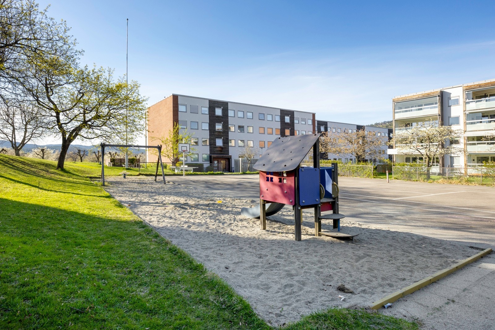Tomten er pent opparbeidet med asfalterte internveier, belegningsstein, gressplener og variert beplantning, lekeapparater og sittegrupper. Galleribilde