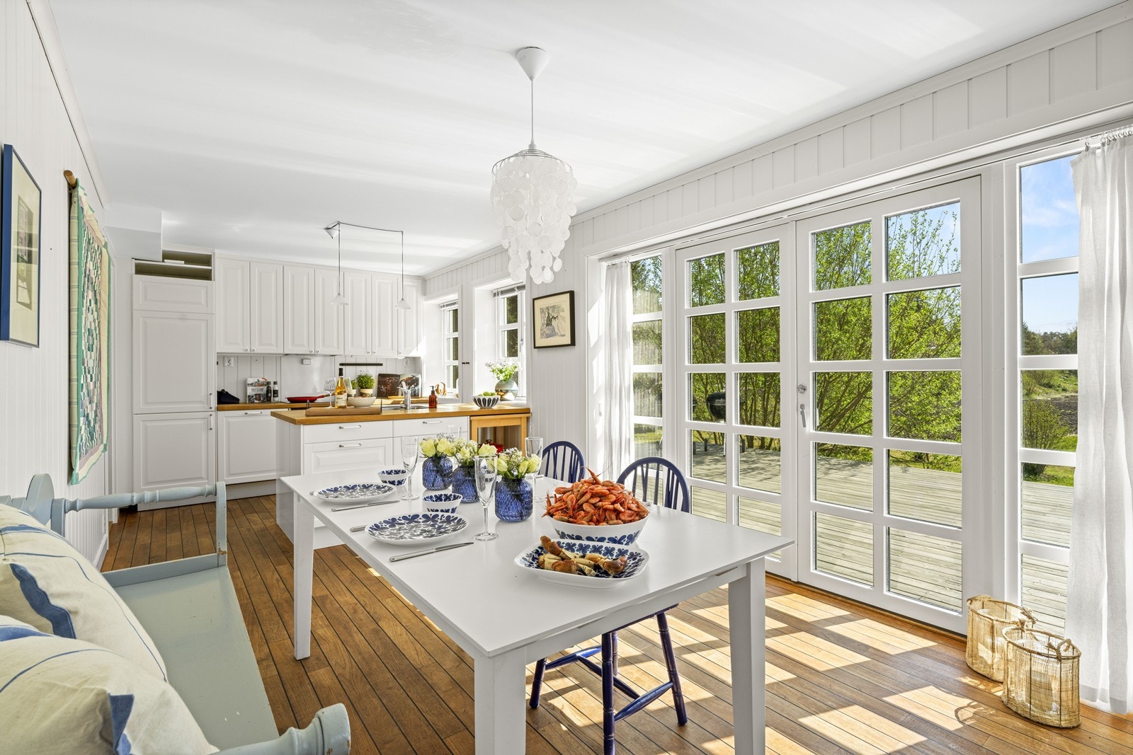 Stue med åpen kjøkkenløsning og doble dører som fører ut i hagen Galleribilde