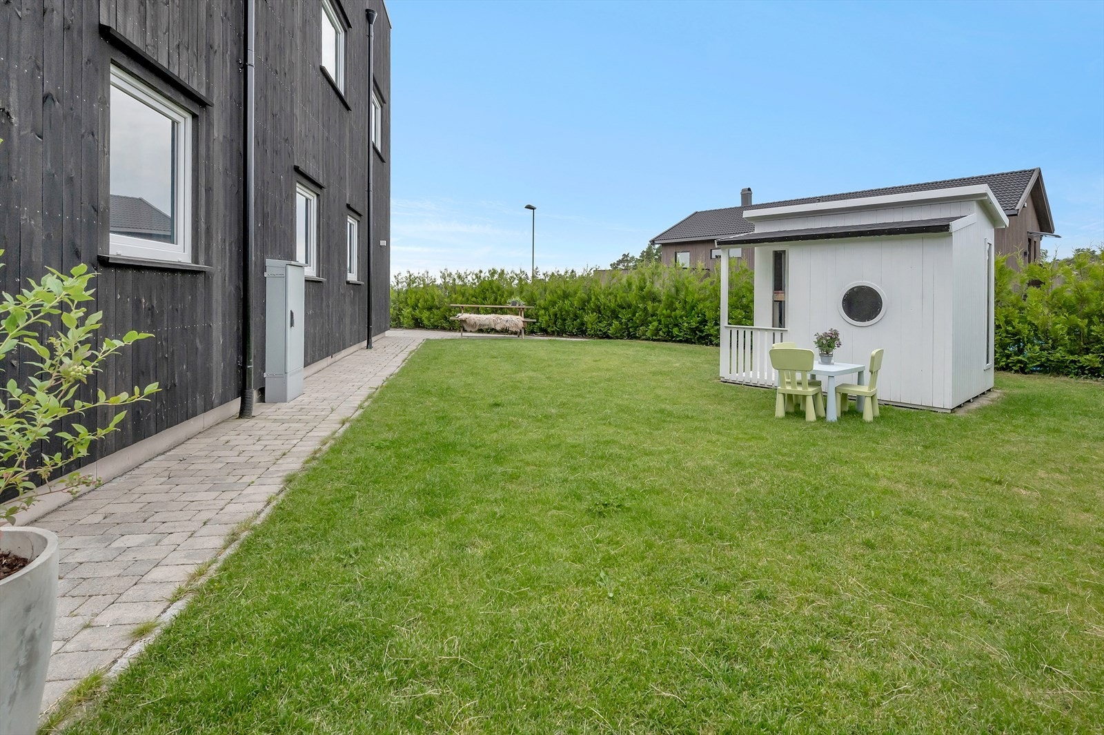 Velstelt hage med brosten inntill husveggen. Galleribilde
